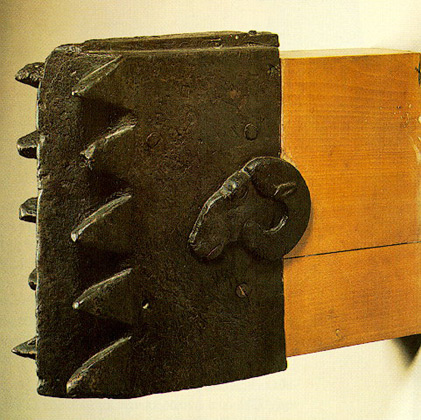 Ο χάλκινος "κριός" είναι η μοναδική στο είδος πολιορκητική μηχανή, που έχει διασωθεί από την αρχαιότητα. Έχει σχήμα ορθογωνίου παραλληλεπιπέδου. Η μία στενή πλευρά απολήγει σε μεγάλα δόντια και στην άλλη προσαρμοζόταν ο ξύλινος στειλεός, που δεν διατηρήθηκε. Σε κάθε πλατιά πλευρά του διακοσμείται με κεφαλή κριού. Στη διακόσμηση αυτή οφείλει και την ονομασία του. Τα δόντια είναι λυγισμένα και φθαρμένα, γεγονός που φανερώνει ότι είχε χρησιμοποιηθεί ως πολιορκητική μηχανή πριν αφιερωθεί στο ιερό του Δία της Ολυμπίας. Χρονολογείται στο πρώτο μισό του 5ου αι. π. Χ. και ίσως είναι σικελικού εργαστηρίου.